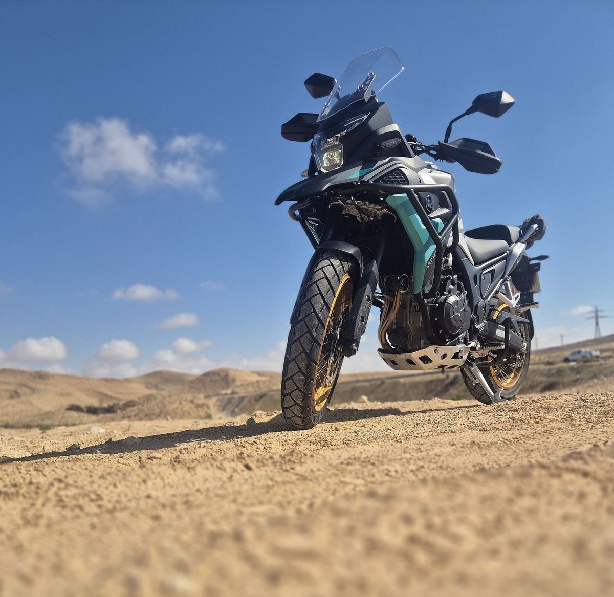 קוב 510X ניצב על שביל עפר במדבר, מבט מהחזית, על רקע גבעות מדבר ושמיים מעוננים