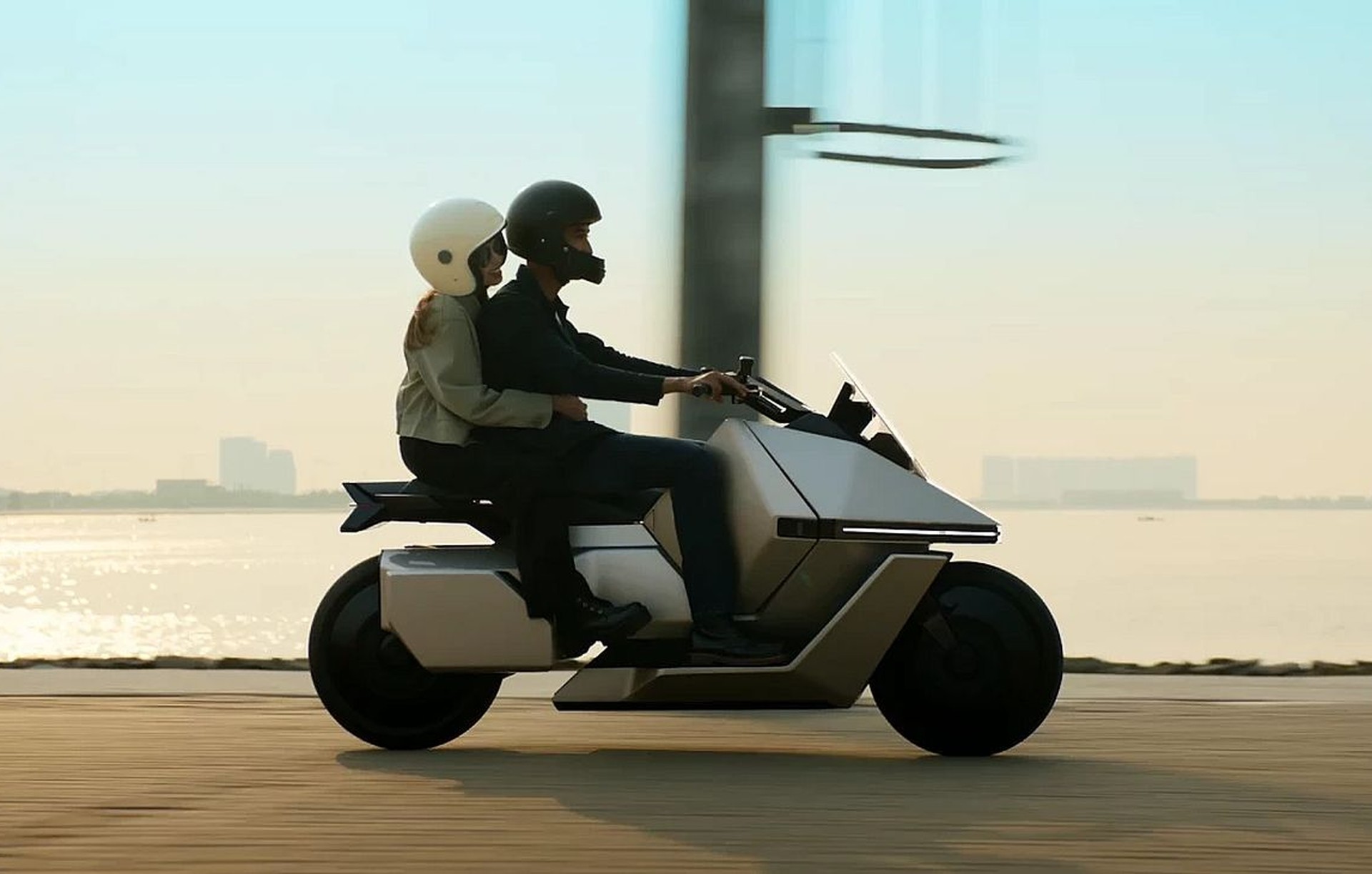 הקטנוע החשמלי OMO-X של OMOWAY בנסיעה עירונית עם שני רוכבים, עיצוב עתידני
